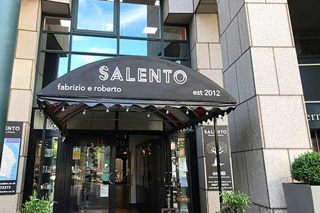 The Salento restaurant front with a black umberella arch and green planters.