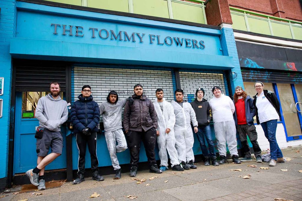 Stood in front of the blue Tommy Flowers pub are the volunteers who built it