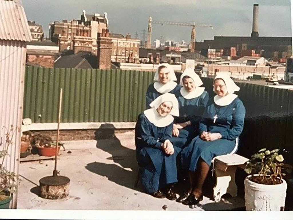 Four nuns in white habits sat on the mission house roof in the sun