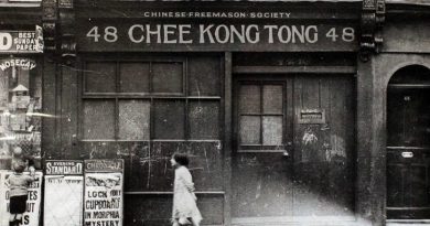 Old photograph of Limehouse Chinatown, with a young child walking in front of a Chinese freemason society.