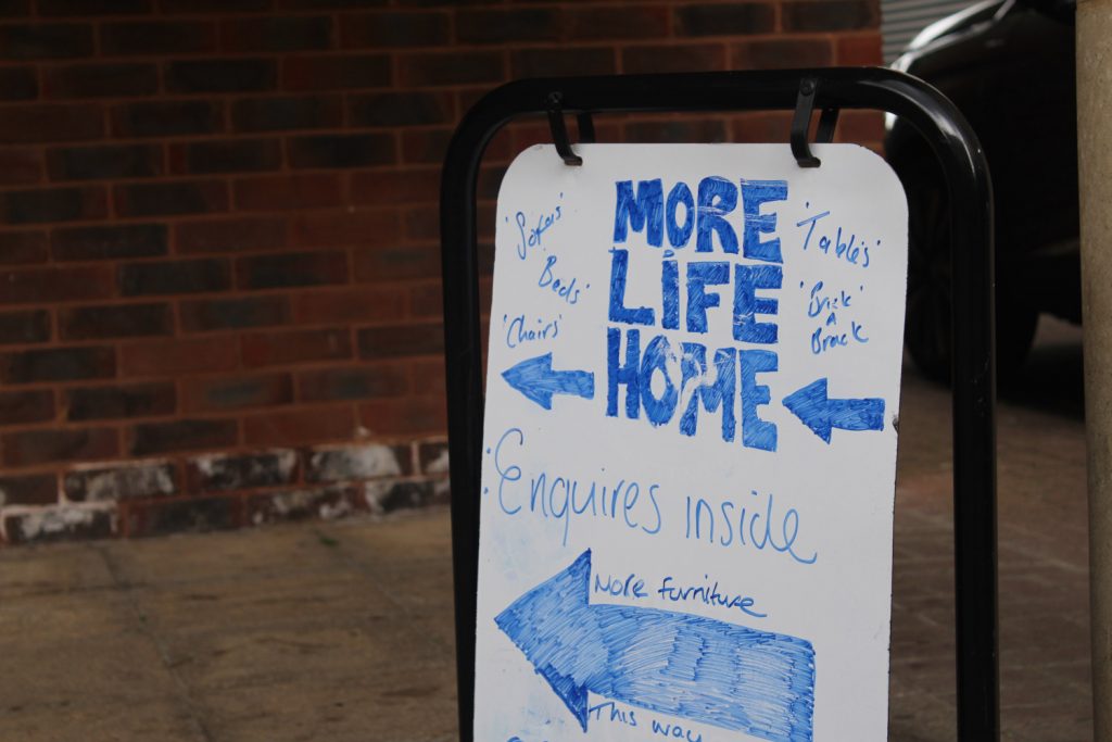 Blue and white sign for More Life Home recycled furniture store, Isle of Dogs, East London
