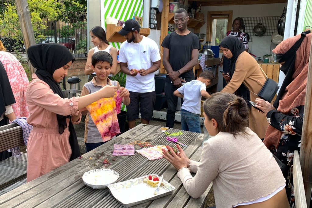 A tie dying workshop takes place in the R-Urban garden, with the community kitchen in a shipping container behind, Poplar, East London
