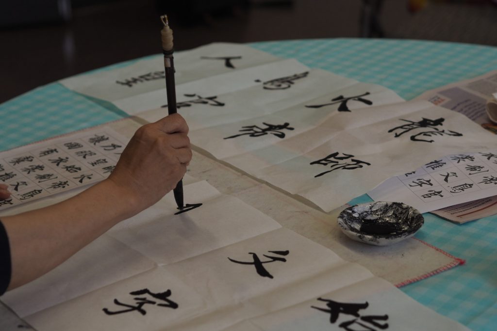A lady writes Chinese characters with a calligraphy brush at the Chinese Association of Tower Hamlets.