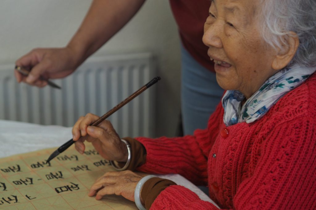 An older lady practices calligraphy at the Chinese Association of Tower Hamlets. 