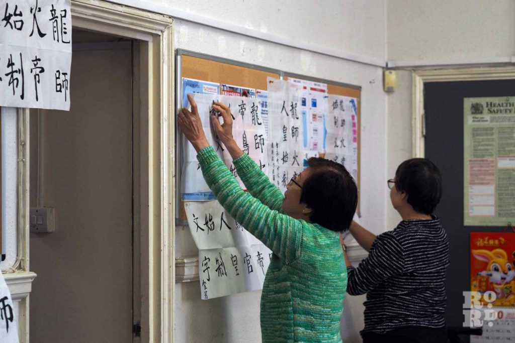 Calligraphy being hung on the wall before a class at the Chinese Association of Tower Hamlets in Limehouse.