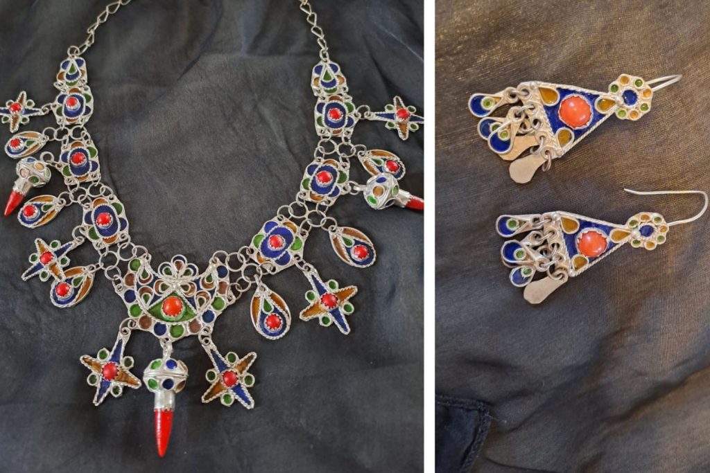 Traditional silver Berber necklace and earrings, with multicoloured stones on a piece of black fabric.