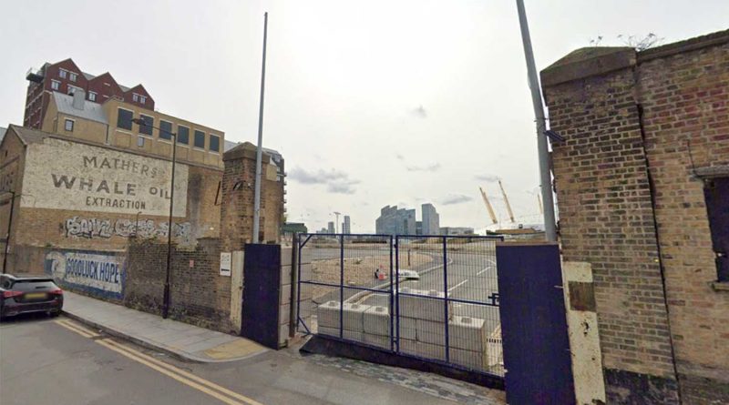 The gates in front of the Orchard Wharf development site, flanked by buildings with the O2 in the distance, Poplar, east London